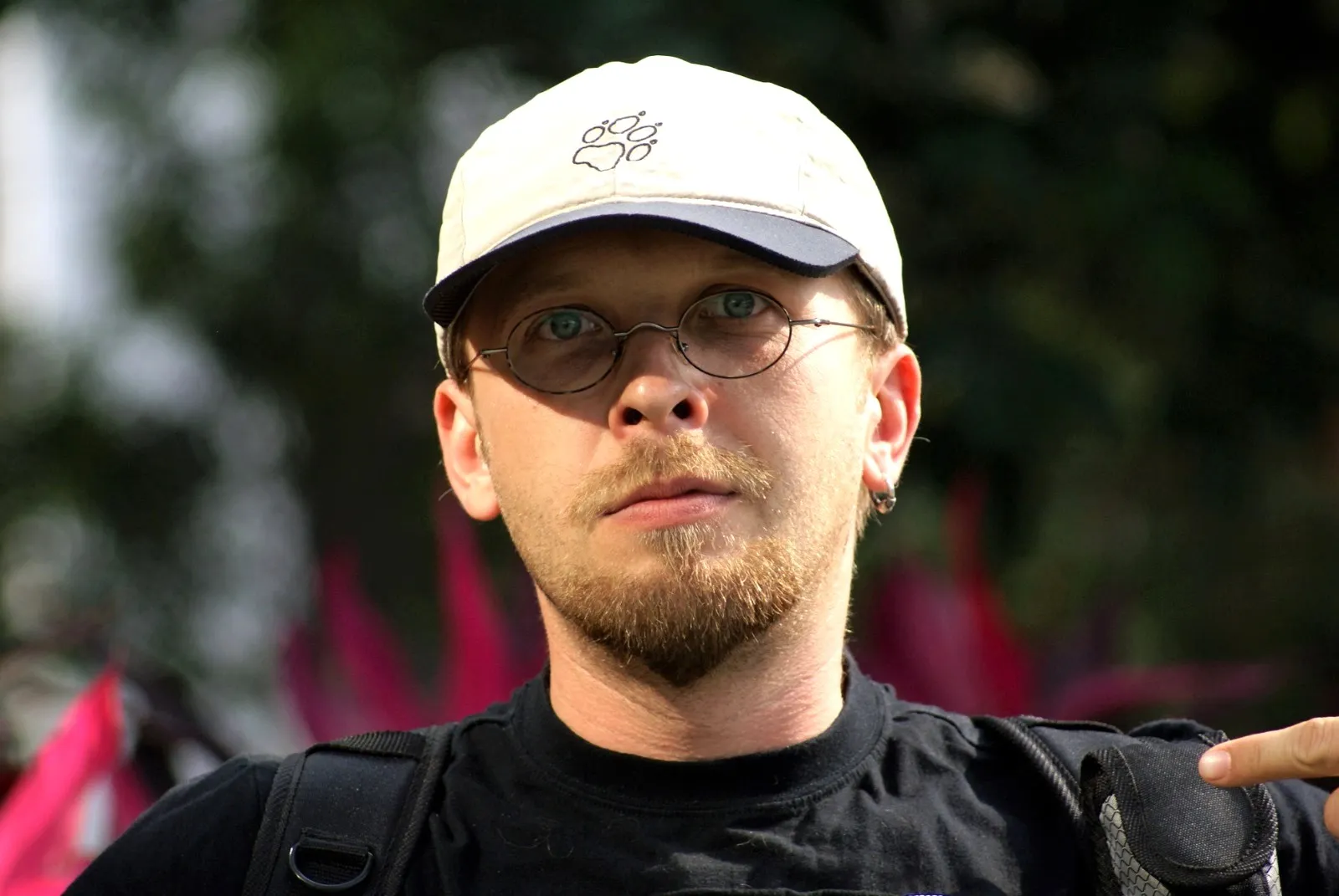 Marcin Wierzba w jasnej czapce i okularach, z plecakiem na ramionach.