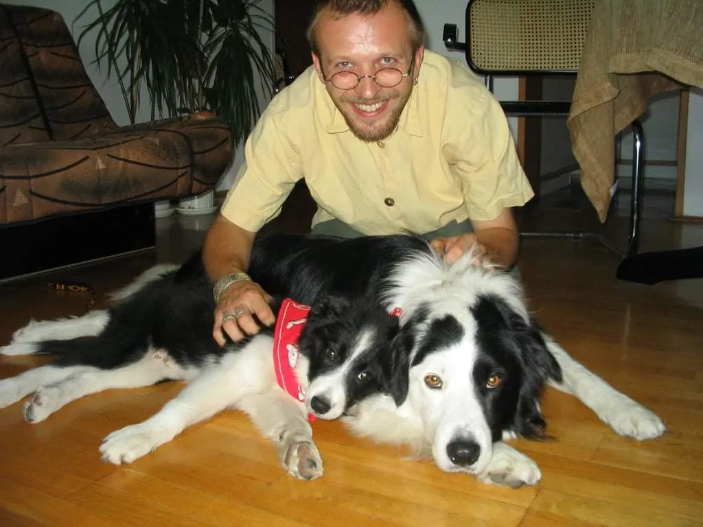 Uśmiechnięty Marcin Wierzba z dwoma czarno-białymi psami.