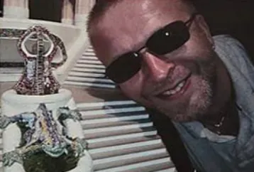 Marcin Wierzba w okularach przeciwsłonecznych obok ozdobnej rzeźby.